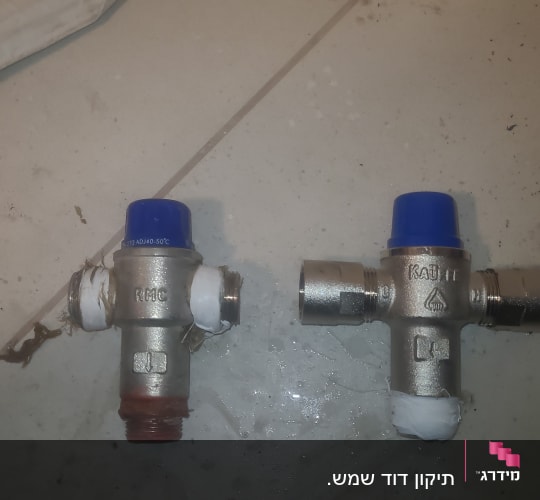 שני שסתומים עם כובעים כחולים על רצפה לבנה